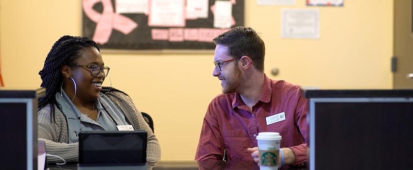 Two workers in Career Services talking at a desk.